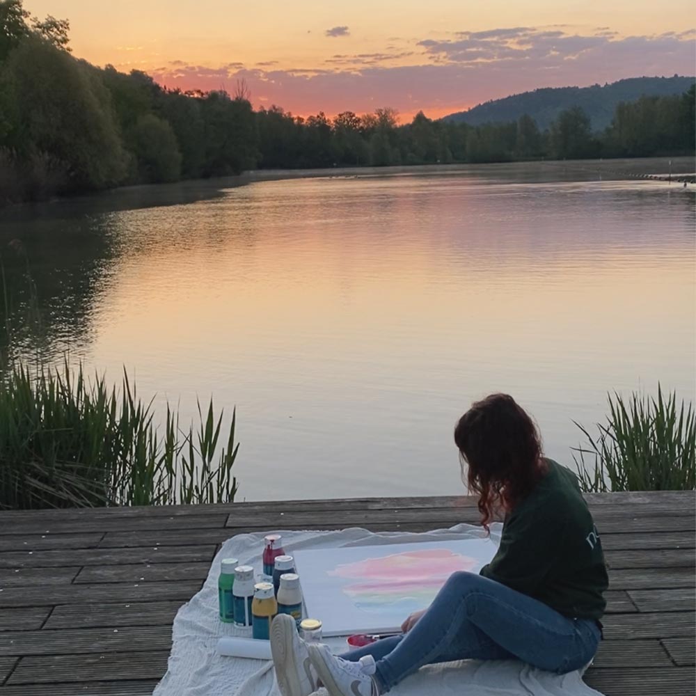 Künstlerin Noenya malt Sonnenaufgang am See